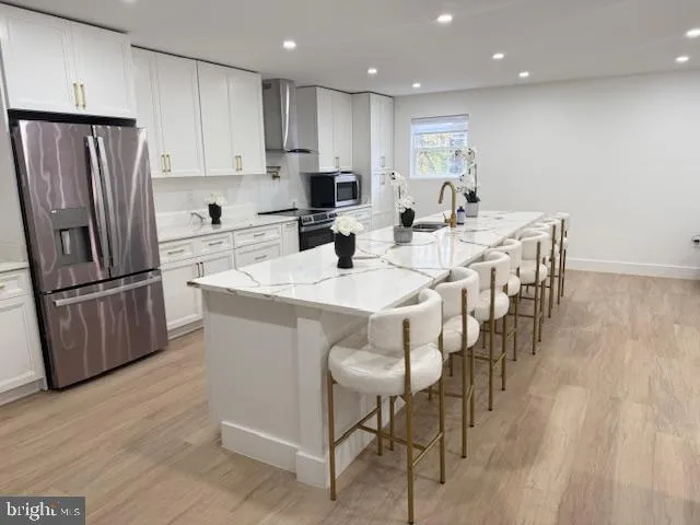 a kitchen with stainless steel appliances granite countertop a refrigerator a sink a stove a dining table and chairs