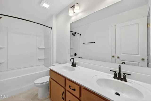 a bathroom with a bathtub shower sink vanity mirror and toilet
