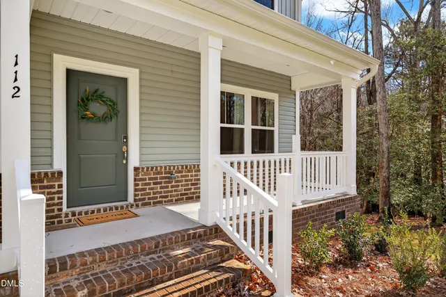a porch with a bench next to a small yard