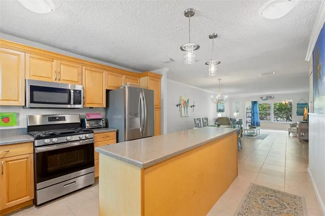 a large kitchen with kitchen island a large counter top space a sink stainless steel appliances and cabinets