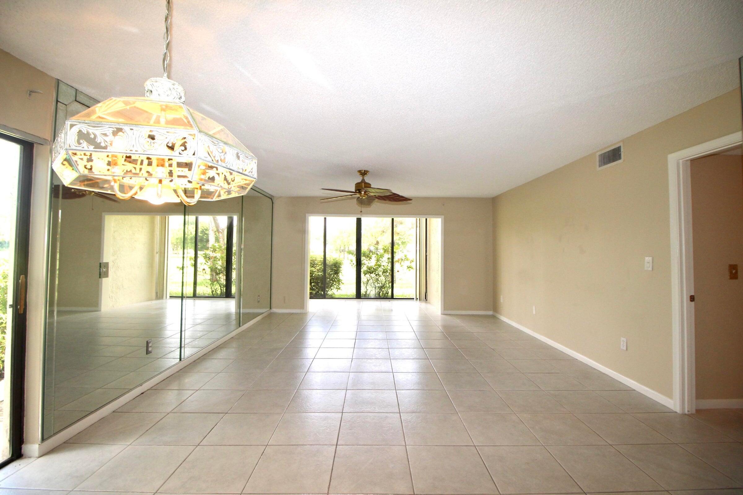 21766 Cypress Drive, Unit 20A Boca Raton, FL 33433 - Photo 13 of 21 a view of an empty room with a chandelier fan and a fireplace