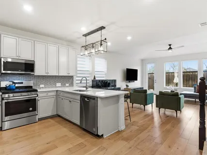 a kitchen with stainless steel appliances granite countertop a stove top oven a sink dishwasher a dining table and chairs with wooden floor