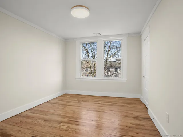 an empty room with wooden floor and window