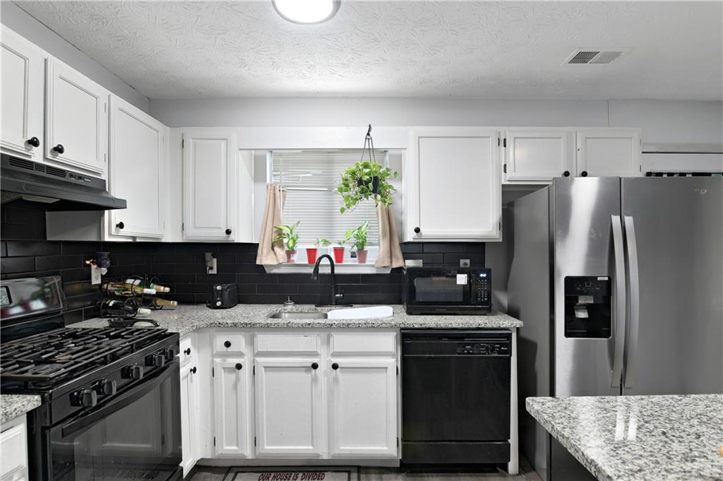 2303 Wingfoot Place Decatur, GA 30035 - Photo 3 of 10 a kitchen with kitchen island granite countertop a sink stove and refrigerator