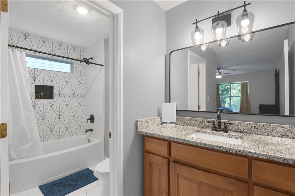 2303 Wingfoot Place Decatur, GA 30035 - Photo 8 of 10 a bathroom with a granite countertop sink a mirror a bathtub and shower