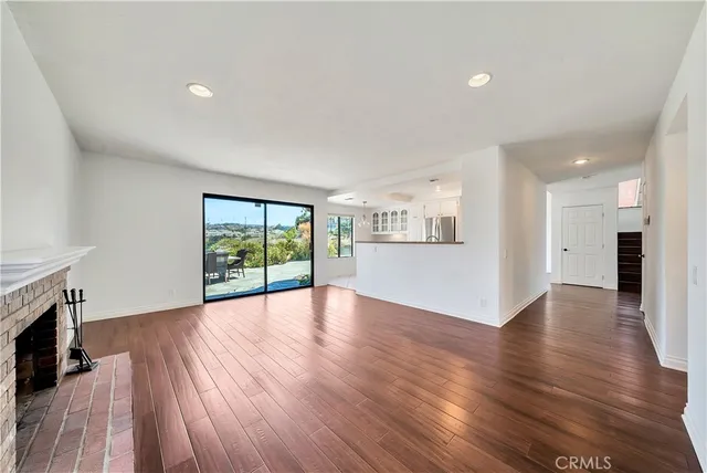 a view of an empty room with wooden floor and a fireplace