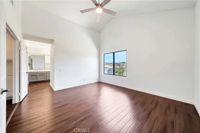 an empty room with wooden floor a ceiling fan and windows