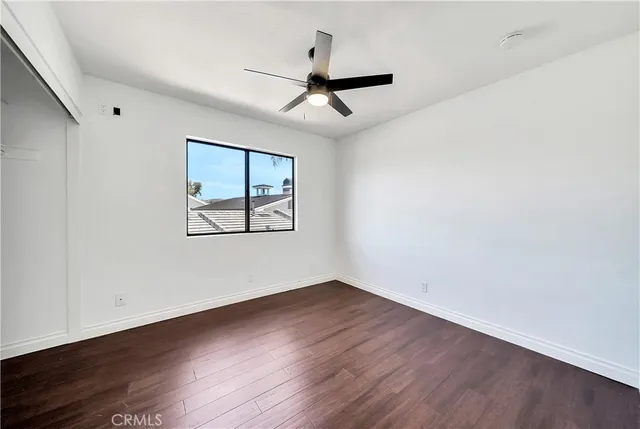 an empty room with wooden floor ceiling fan and windows