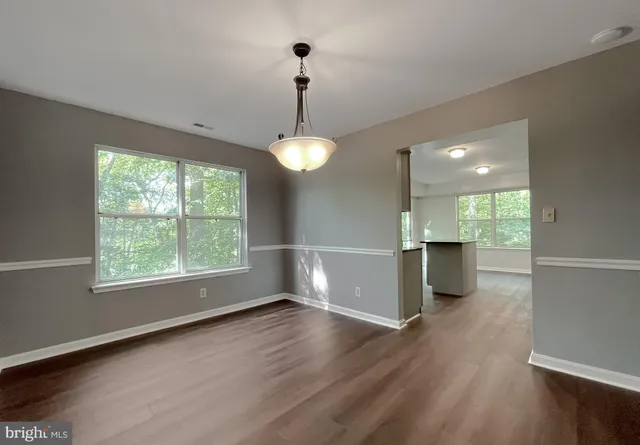 a view of an empty room with window and wooden floor