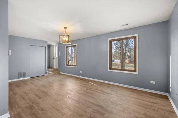 an empty room with windows and chandelier fan