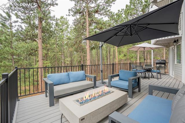 615 Cimarron Road Monument, CO 80132 - Photo 17 of 50 Wooden deck with an outdoor living space with a fire pit, outdoor dining area, and grilling area