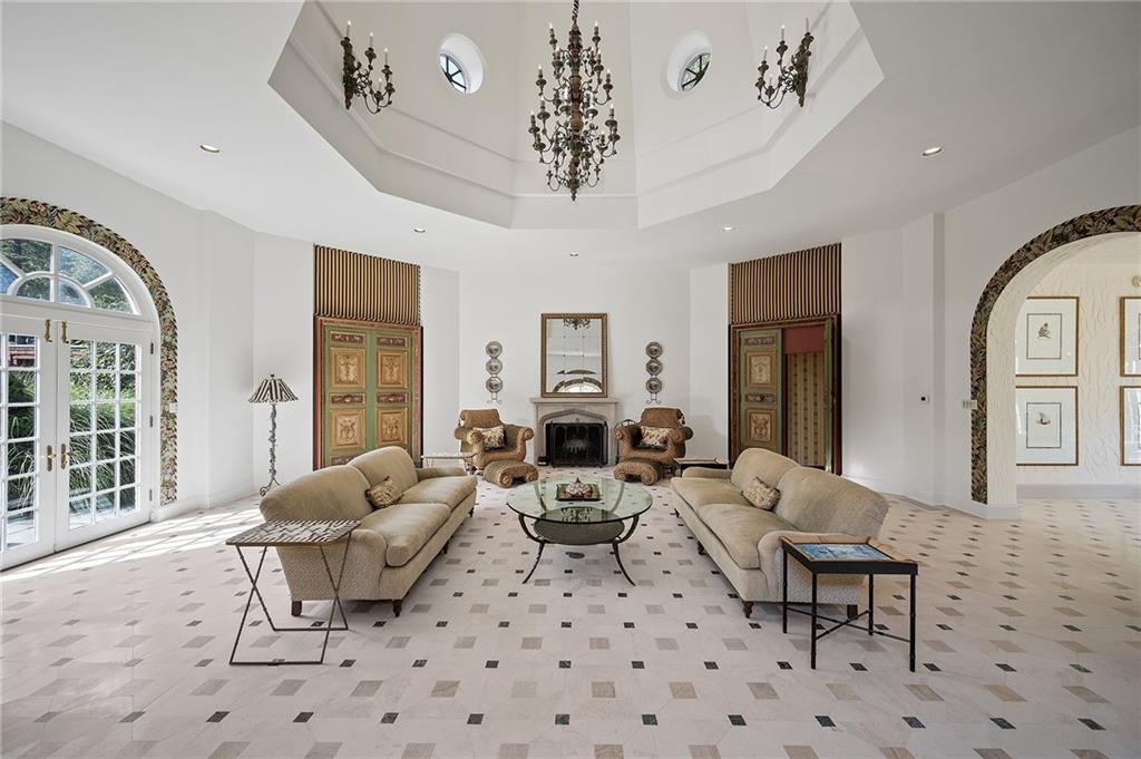 898 Persimmon Road Sewickley, PA 15143 - Photo 29 of 50 The great room, accessed through the arched loggia, features French doors open to the pool terrace, creating seamless indoor-outdoor flow. An airy, light-filled space crowned by a dramatic octagonal tray ceiling with round accent windows and a grand chandelier.