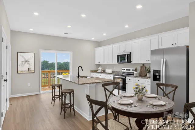 a kitchen with stainless steel appliances granite countertop a stove top oven a refrigerator a sink and dishwasher with wooden floor