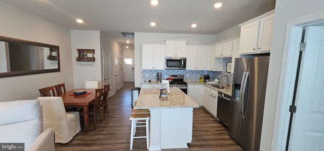 a kitchen with stainless steel appliances kitchen island granite countertop a refrigerator and a dining table