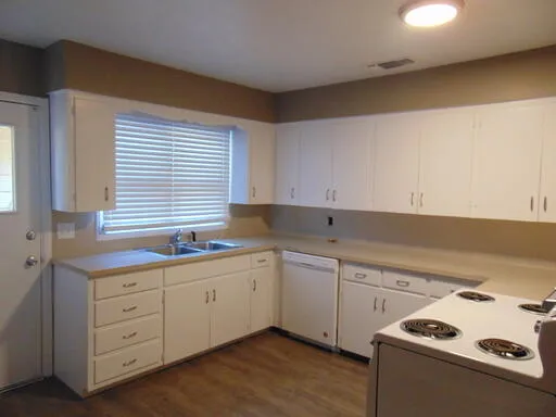 a kitchen with white cabinets a sink and white appliances