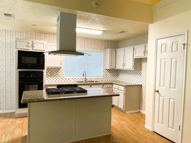 a kitchen with kitchen island granite countertop a sink cabinets and stainless steel appliances
