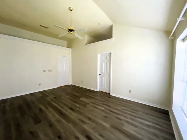 an empty room with wooden floor and ceiling fan