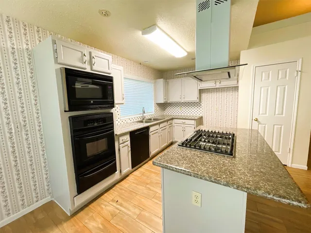 a kitchen with stainless steel appliances granite countertop a stove microwave and sink