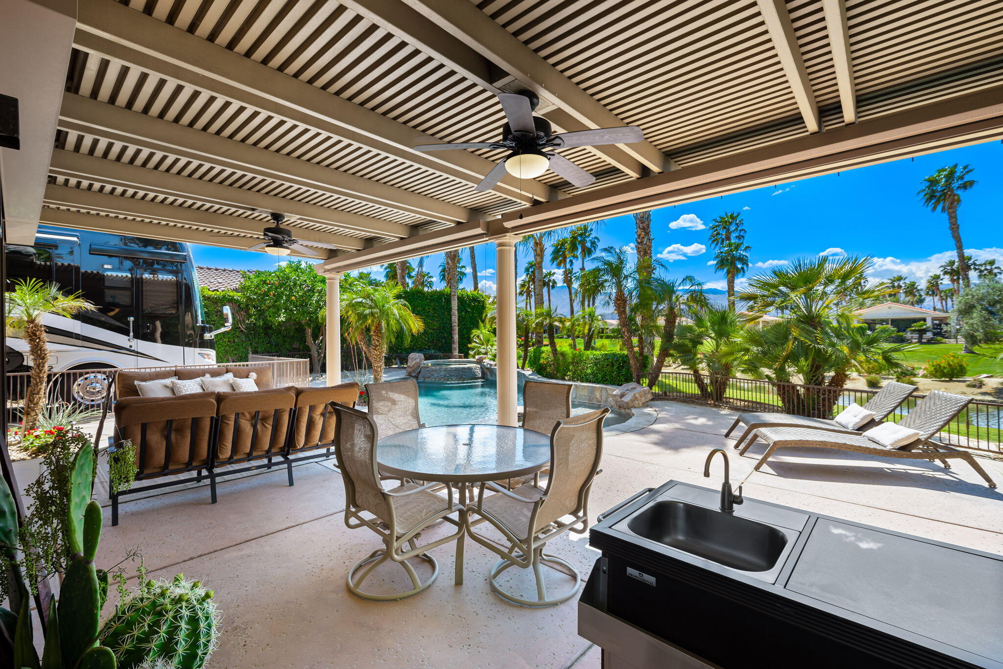 48170 Hjorth Street, Unit 74 Indio, CA 92201 - Photo 13 of 37 a view of a patio with table and chairs potted plants and floor to ceiling window