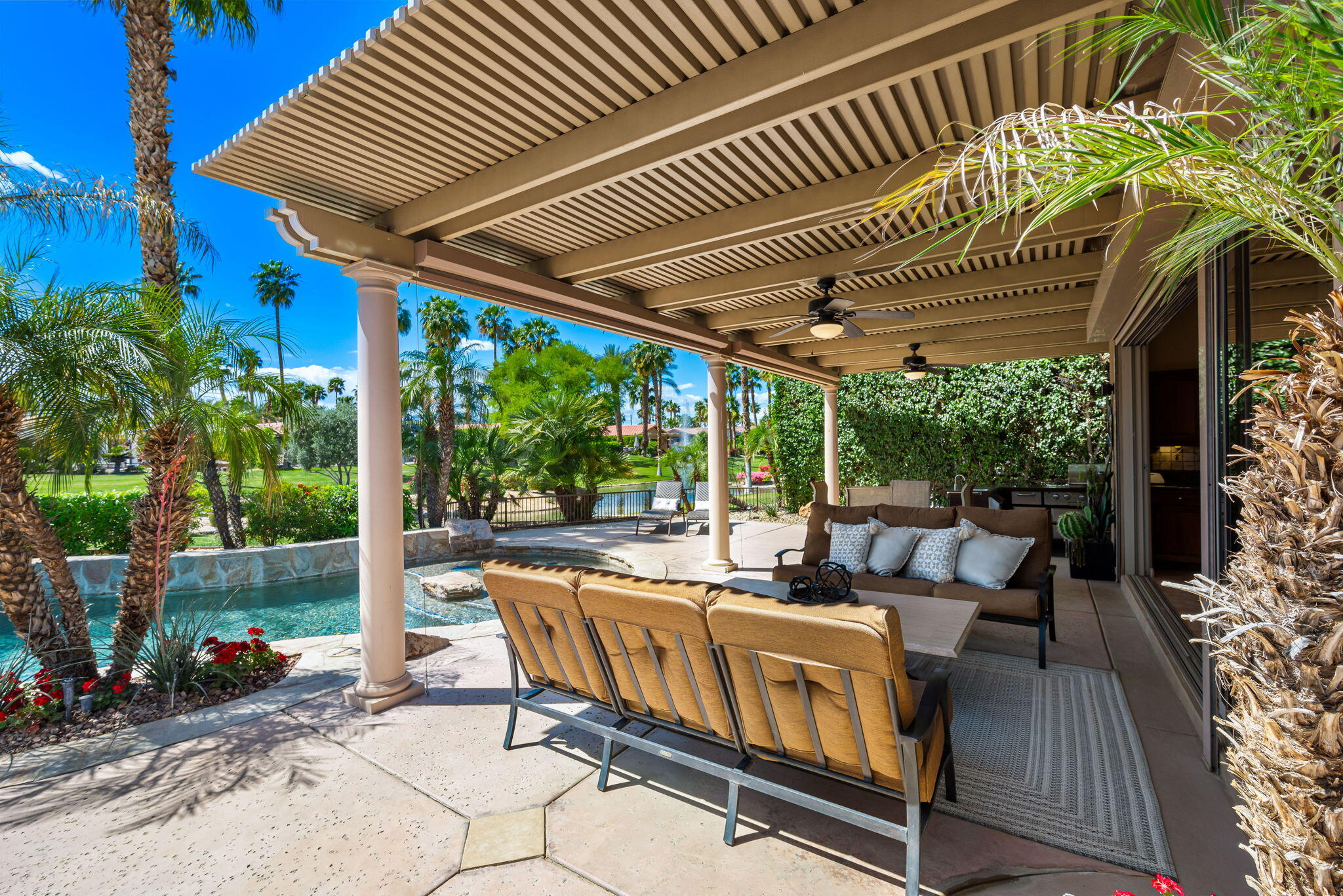 48170 Hjorth Street, Unit 74 Indio, CA 92201 - Photo 7 of 37 a view of a patio with table and chairs potted plants and floor to ceiling window with wooden floor