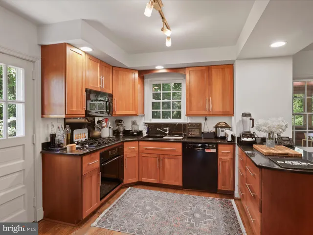 a kitchen with stainless steel appliances granite countertop wooden cabinets a stove a sink a dining table and chairs