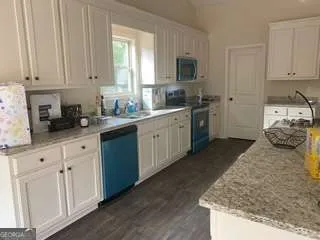 a kitchen with granite countertop white cabinets and white appliances