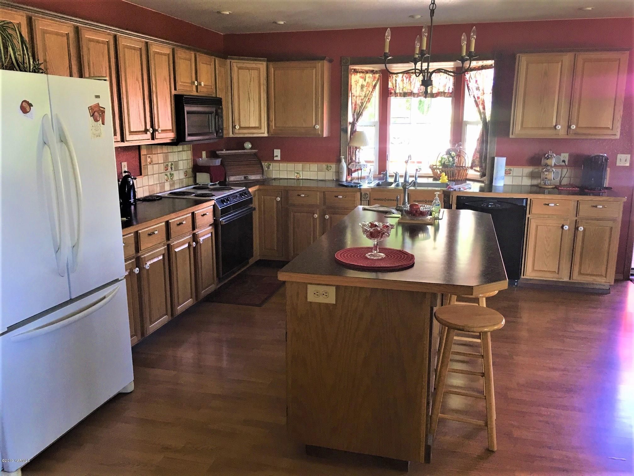 2060 Liberty Road Granger, WA 98932 - Photo 16 of 25 a kitchen with a refrigerator a stove a sink dishwasher and wooden cabinets with wooden floor