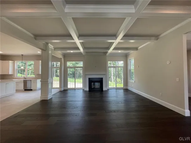 an empty room with wooden floor fireplace and windows
