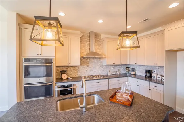 a kitchen with stainless steel appliances granite countertop a sink a stove and refrigerator