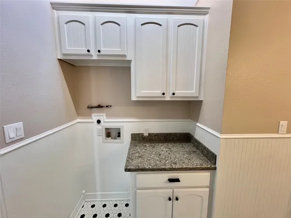 a utility room with granite countertop a sink a stove and cabinets