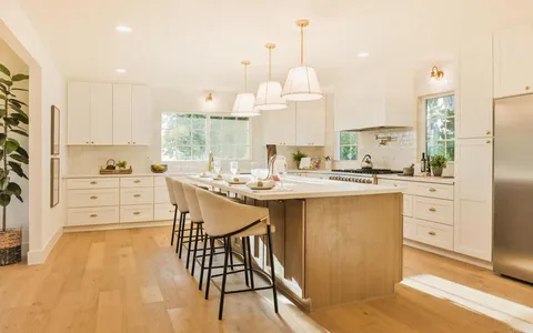 a kitchen with stainless steel appliances kitchen island granite countertop a sink a stove and a refrigerator