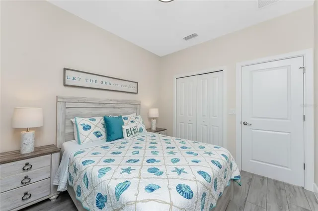 a bedroom with a large bed and a lamp on dresser