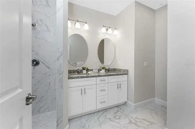 a bathroom with a granite countertop sink a mirror and shower