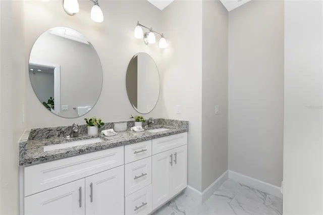 a bathroom with a granite countertop double vanity sink and a mirror