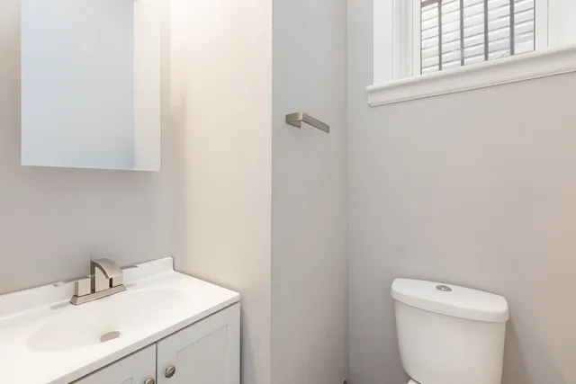 a bathroom with a toilet sink vanity and mirror