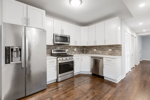 a kitchen with cabinets stainless steel appliances and wooden floor