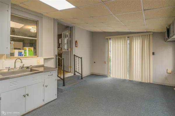 an empty room with a chandelier fan and windows