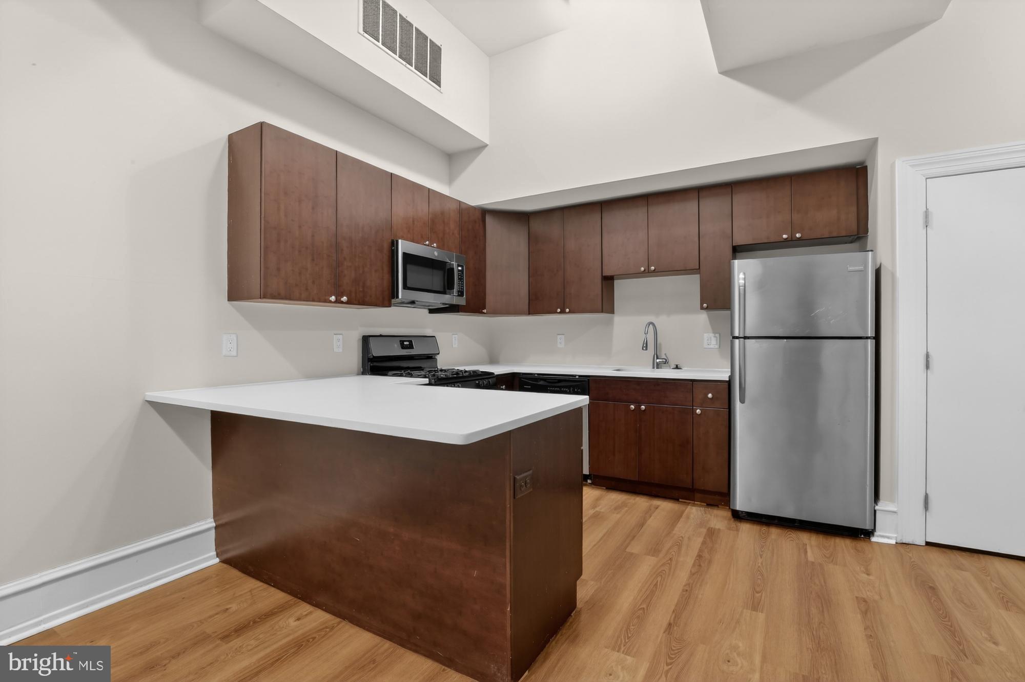 2136 East Dauphin Street, Unit 101 Philadelphia, PA 19125 - Photo 13 of 30 a kitchen with a refrigerator a microwave a sink and cabinets