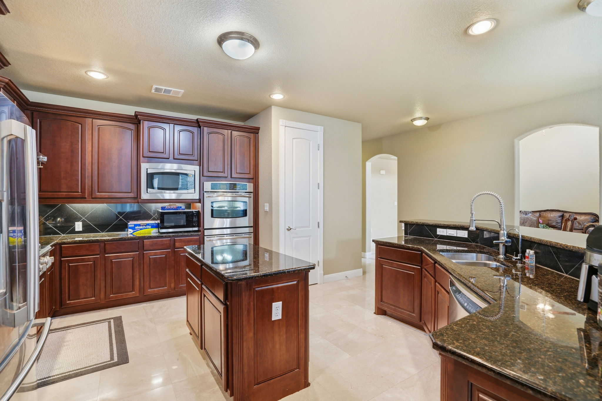 222 Vailco Lane Austin, TX 78738 - Photo 16 of 39 Kitchen featuring dark wood cabinetry, stainless steel appliances, granite countertops, and a central island