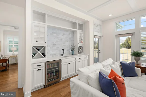 a living room with furniture white cabinets and wooden floor