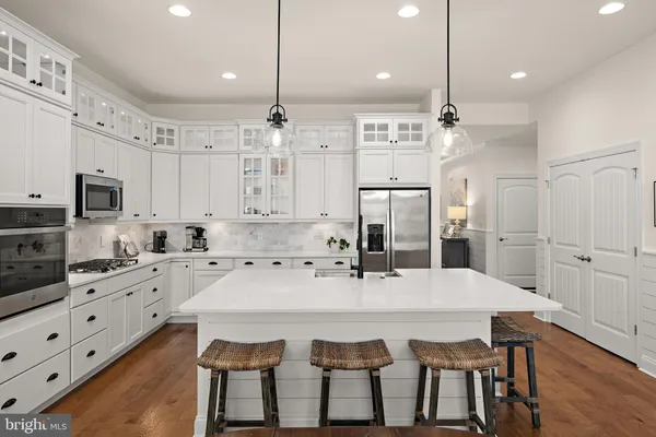 a kitchen with stainless steel appliances kitchen island granite countertop a table chairs sink and cabinets