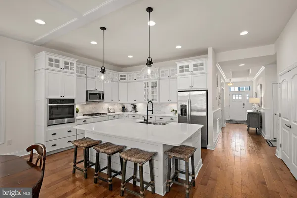 a kitchen with stainless steel appliances kitchen island granite countertop a dining table chairs stove and white cabinets