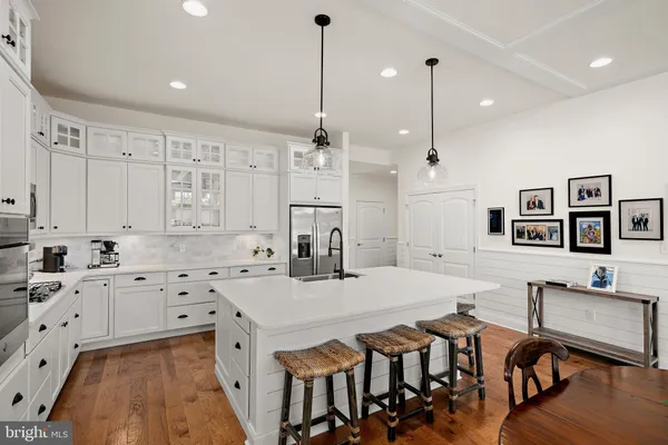 a kitchen with stainless steel appliances sink stove and white cabinets with wooden floor