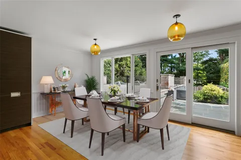 a dining room with wooden floor and a floor to ceiling window