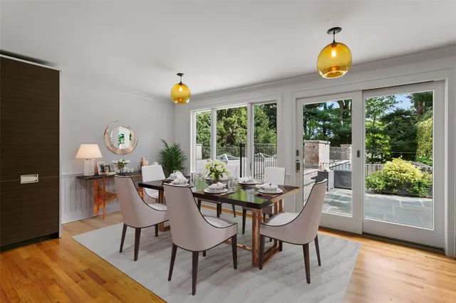 a dining room with wooden floor and a floor to ceiling window