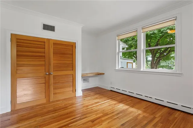 a view of empty room with wooden floor and fan
