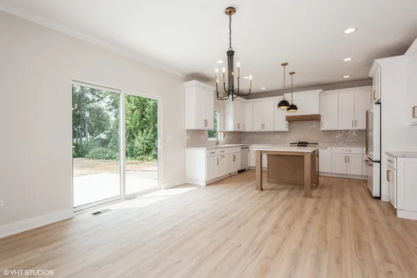 a kitchen with stainless steel appliances a stove top oven a sink a refrigerator a center island and cabinets