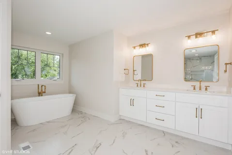 a spacious bathroom with a double vanity sink mirror and bathtub