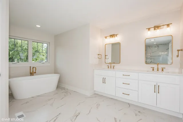 a spacious bathroom with a double vanity sink mirror and bathtub