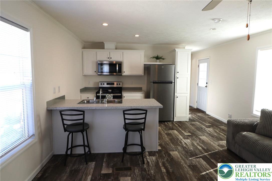5016 Old Timber Road Stroudsburg, PA 18360 - Photo 8 of 34 a kitchen with stainless steel appliances kitchen island granite countertop a stove a refrigerator a sink a table and chairs with wooden floor
